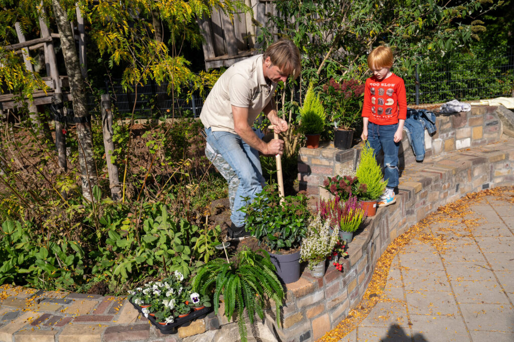 Begeleider plant samen met een leerling in de border op het schoolplein